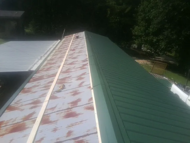 Old rusted panels beside newly installed green metal roofing — Wind Damage Roof Repair by Roofing Brothers in Germantown
