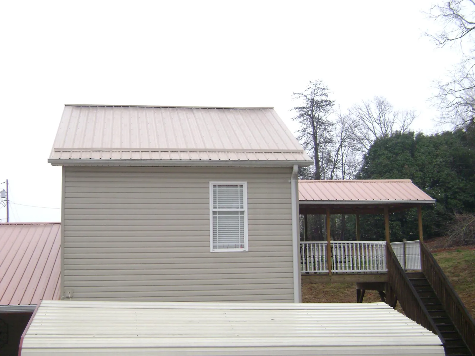 Tan metal roofs on a two story addition and attached porch, from a Roof Replacement job in Germantown